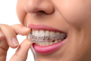 A woman putting her teeth into an invisalign.