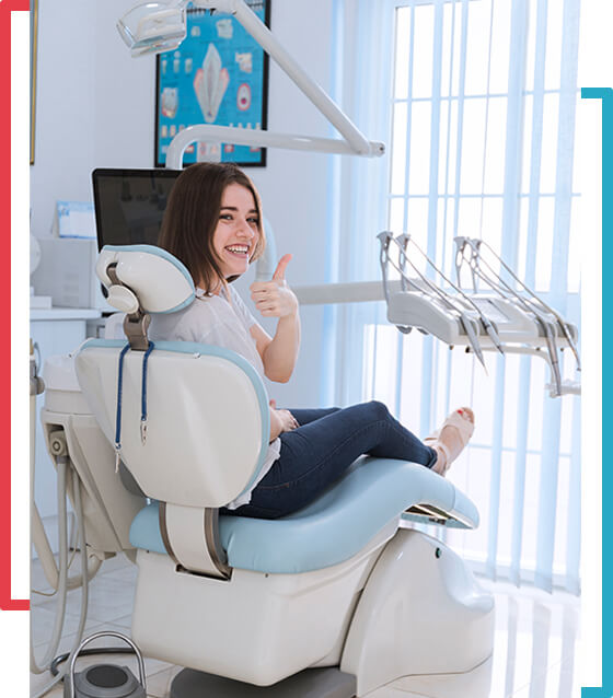 A woman sitting in the dentist chair giving thumbs up.