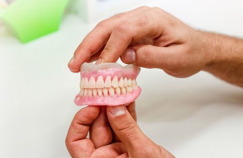 A person holding a fake denture in their hand.